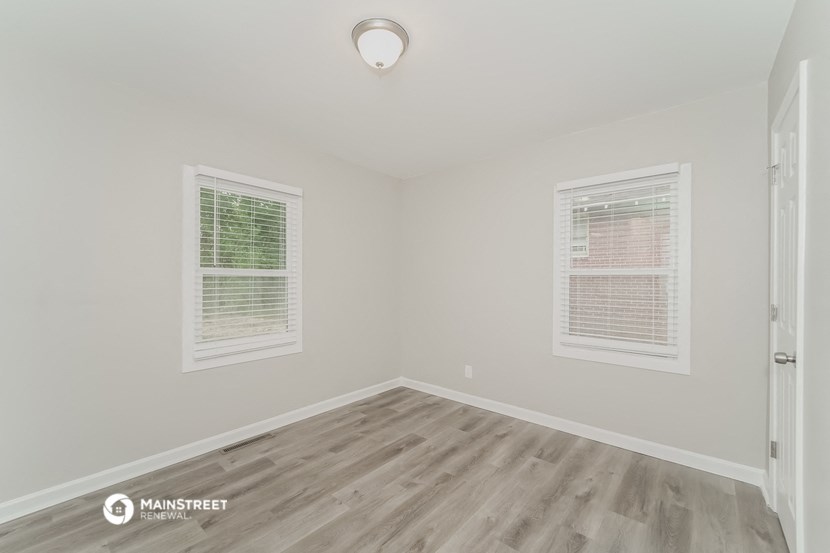 the spacious living room with wood flooring and two windows