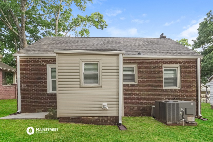 a small brick house with a grey roof and a yard