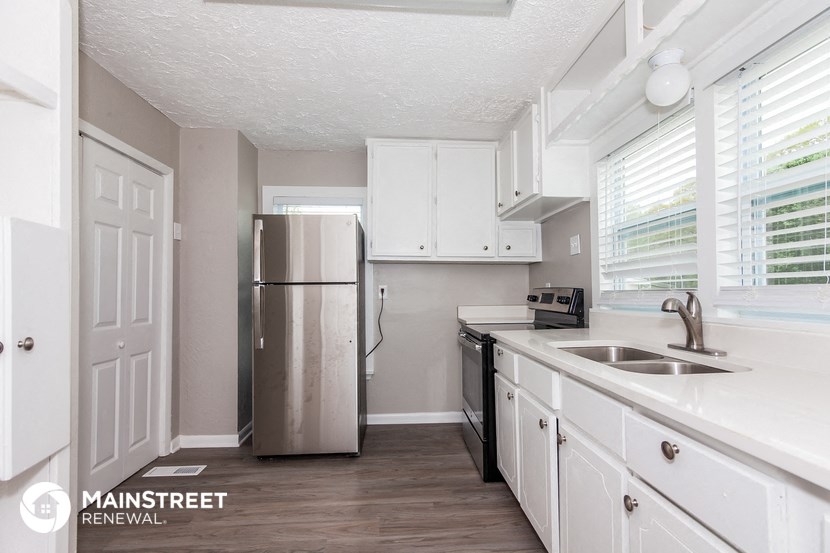 a kitchen with white cabinets and a stainless steel refrigerator