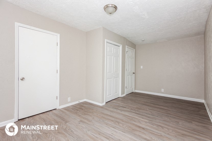 the living room of an apartment with wood floors and white walls