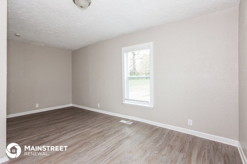 the interior of an empty room with wood floors and a window