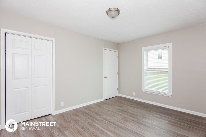 the living room of an apartment with wood floors and a white door