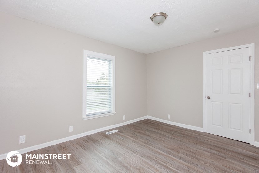 the upstairs bedroom with hardwood flooring and a white door