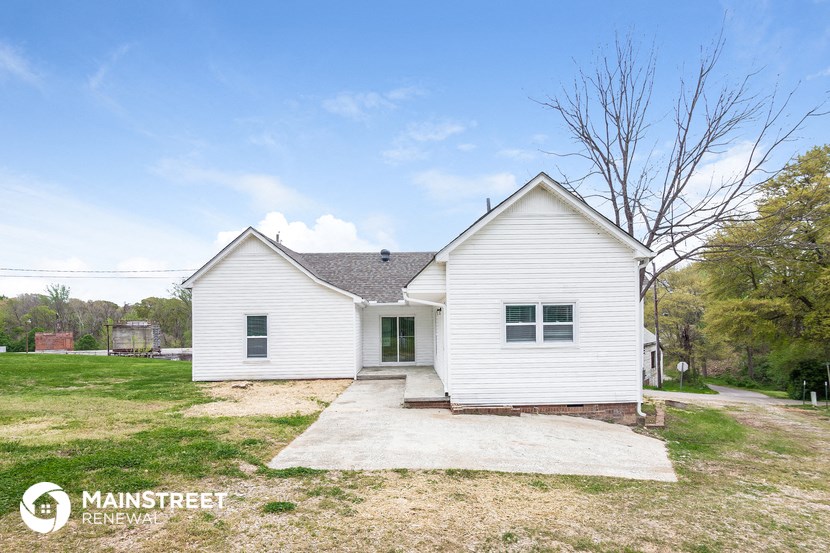 the front of a white house with a paved driveway