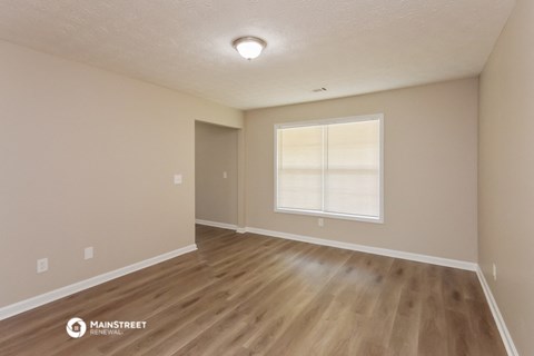 the spacious living room with hardwood flooring and a window