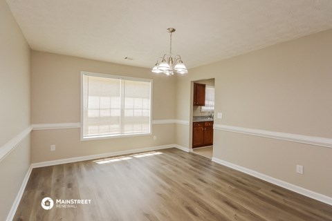 the spacious living room with hardwood flooring and a large window
