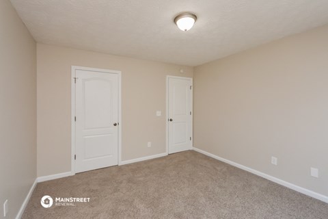 a bedroom with two doors and a carpeted floor