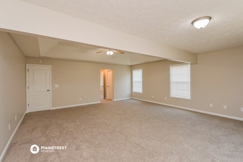 the spacious living room and dining room of an empty house