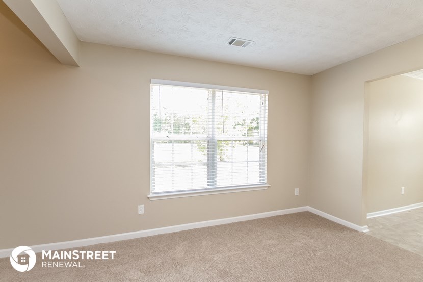 a bedroom with a large window and beige walls and carpet