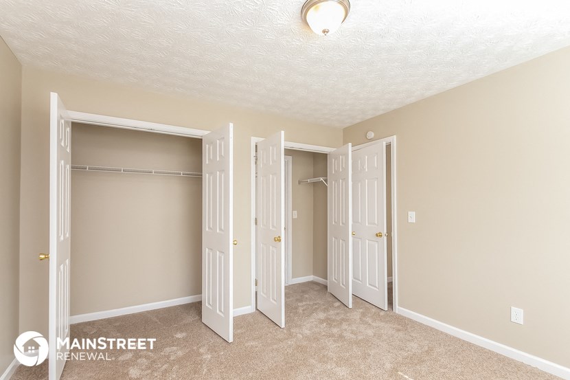 a bedroom with three closets and a carpeted floor