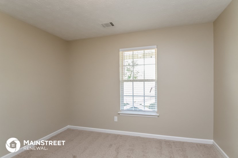 a bedroom with a window and a carpeted floor