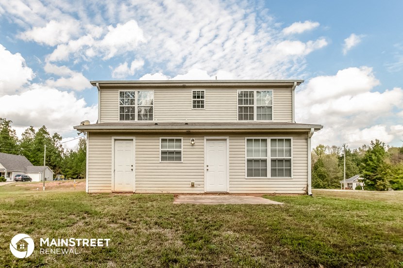 the front of a white house with two white doors and a lawn
