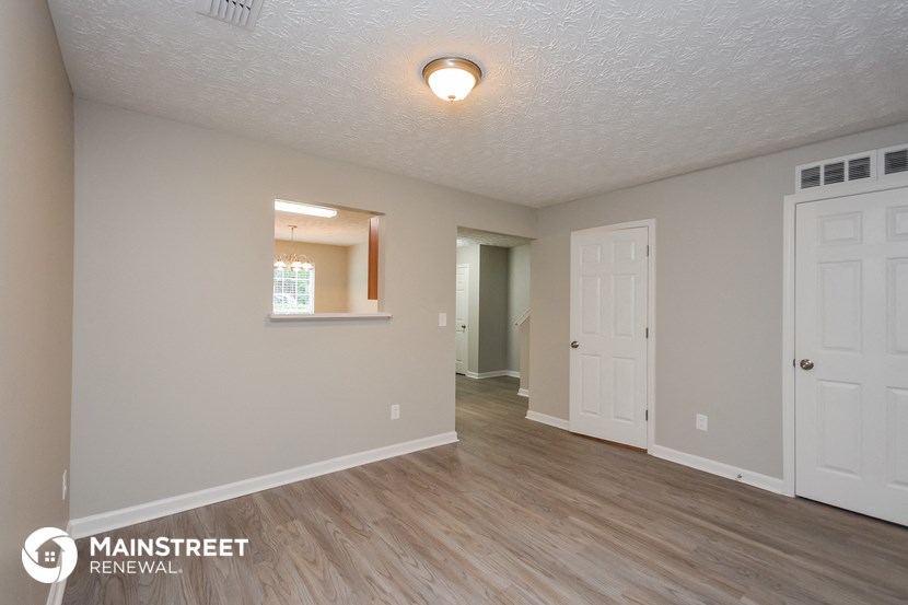 the spacious living room and dining room with white doors and wood flooring