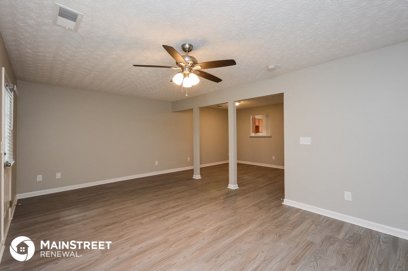 the spacious living room with ceiling fan and wood flooring