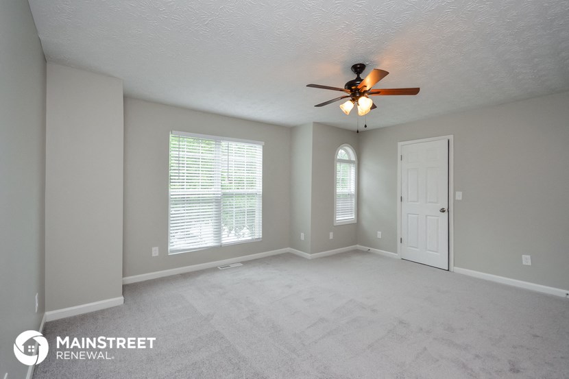 the spacious living room with ceiling fan and large window