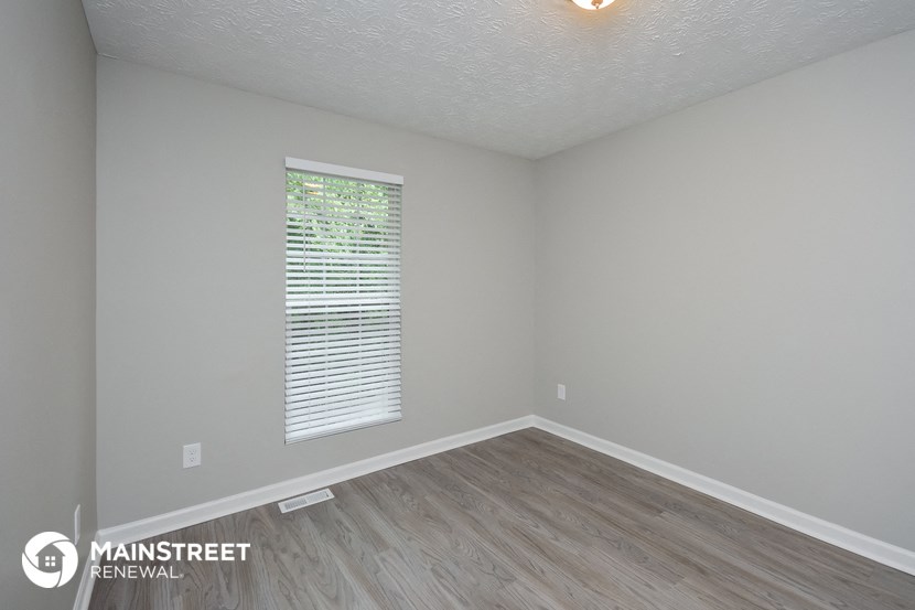 the interior of an empty room with wood flooring and a window