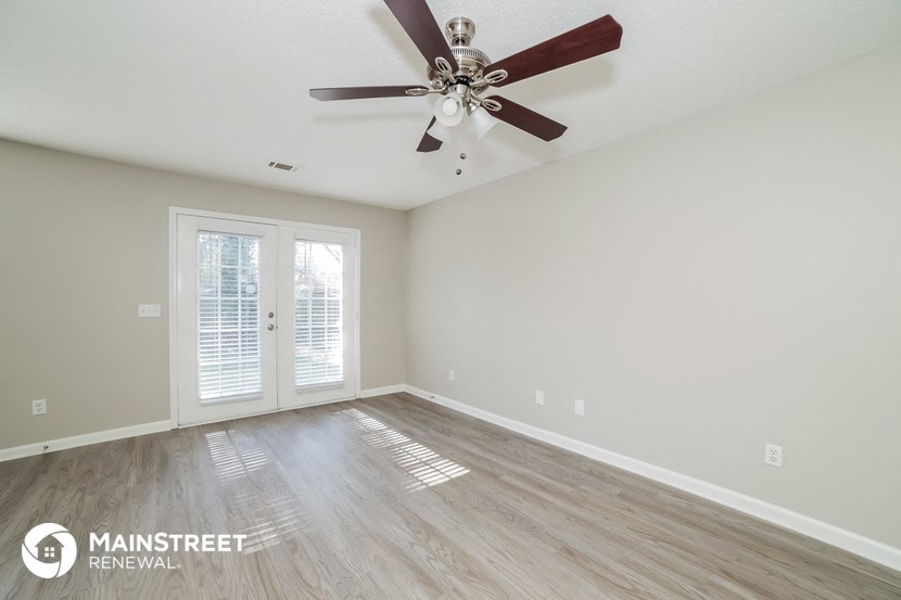 the spacious living room with ceiling fan and wood flooring