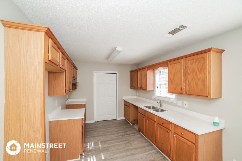 a kitchen with wooden cabinets and white counter tops and a sink
