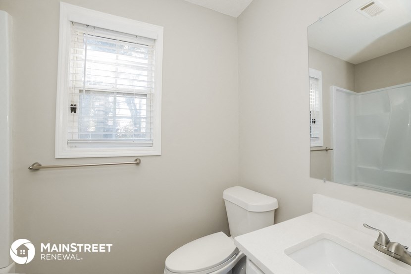 a white bathroom with a sink toilet and a window