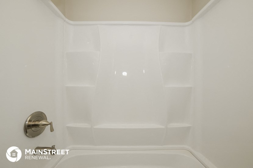 a white bathtub with white tile in a bathroom with a silver faucet