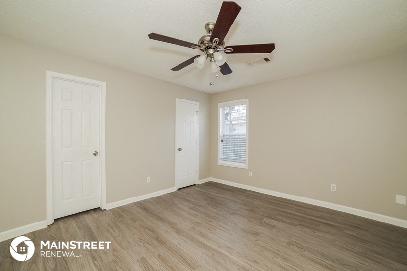 the spacious living room with ceiling fan and hardwood floors