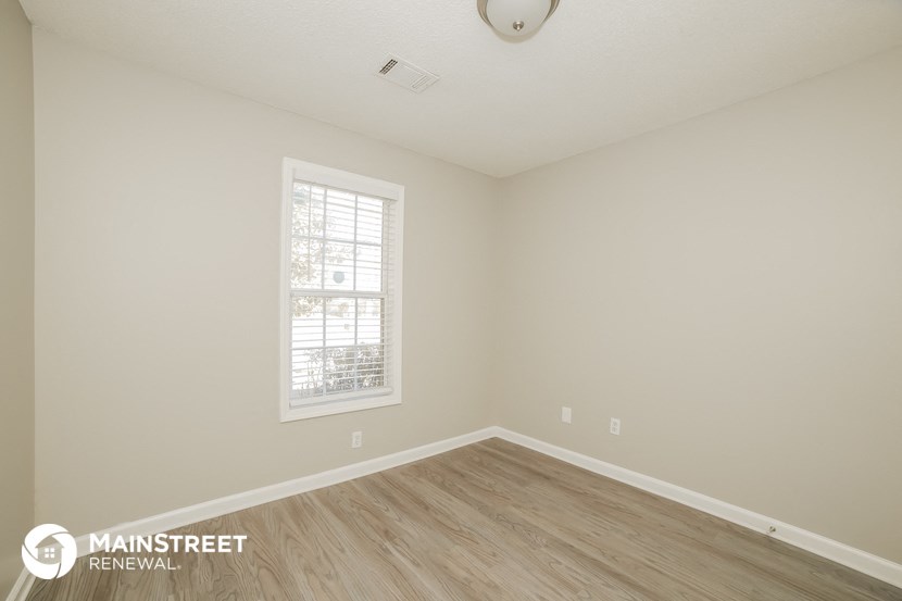 the interior of an empty room with wood floors and a window
