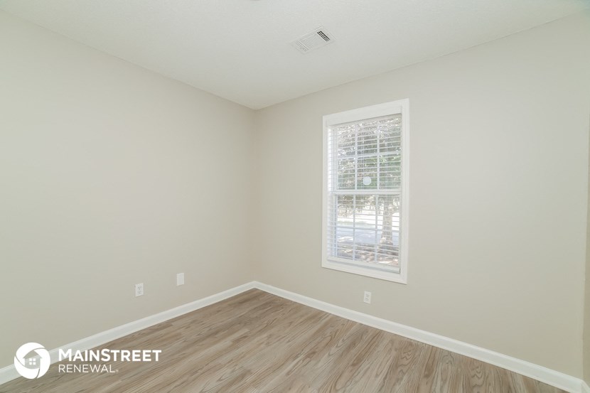 the upstairs bedroom with hardwood flooring and a window