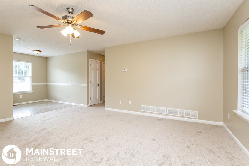 an empty living room with a ceiling fan
