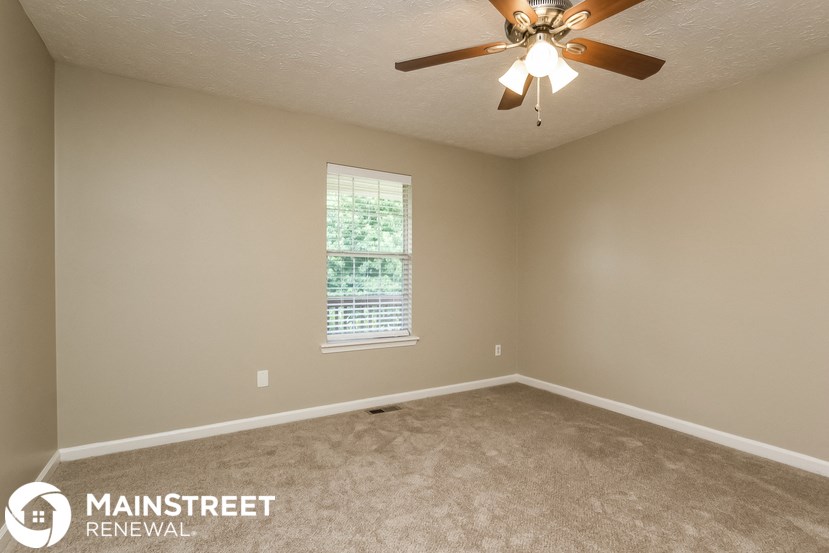 an empty living room with a ceiling fan and a window