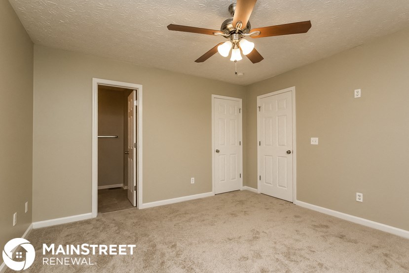 an empty living room with a ceiling fan and two doors