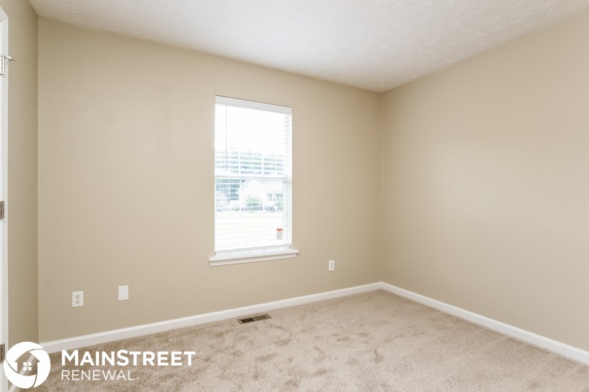 a bedroom with a window and a carpeted floor