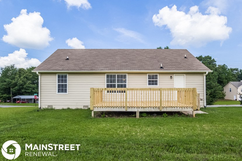 a small yellow house with a wooden porch and a wooden bench