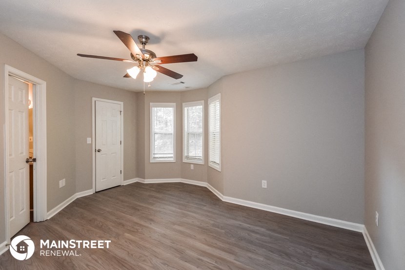 the spacious living room with ceiling fan and wood flooring