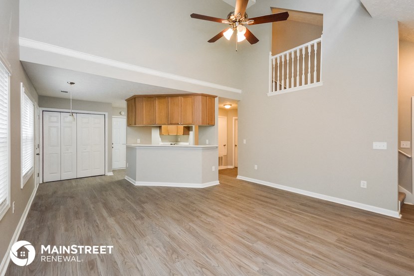 the living room and kitchen of an open floor plan with a ceiling fan