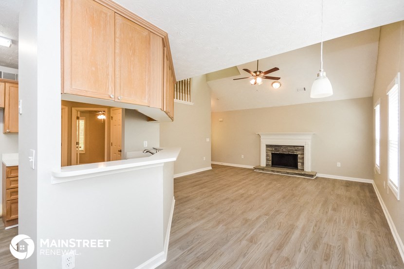 a living room with a fireplace and a kitchen with wood flooring