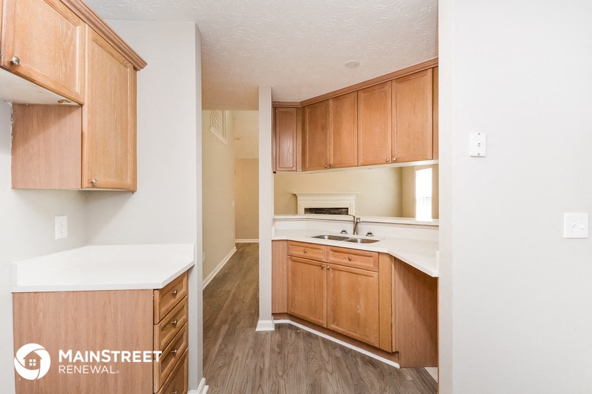 a kitchen with wooden cabinets and white counter tops and a sink