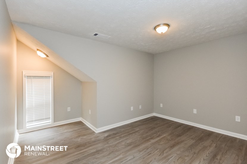 the spacious living room with wood flooring and white walls