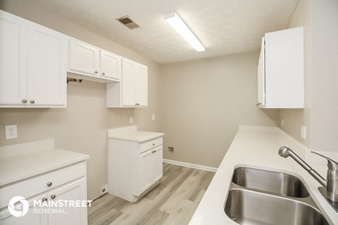 a kitchen with white cabinets and white counter tops and a sink