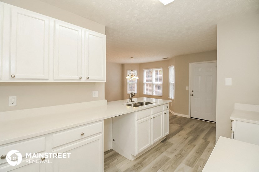 a kitchen with white cabinets and a sink and a window