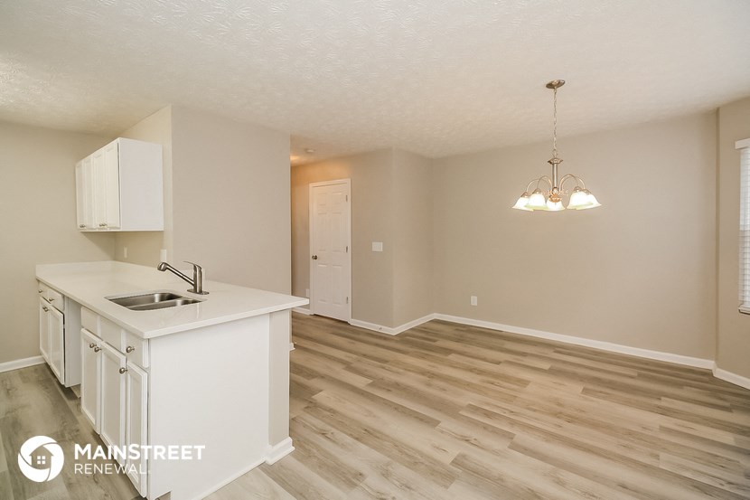 a kitchen and living room with a white counter top and a sink