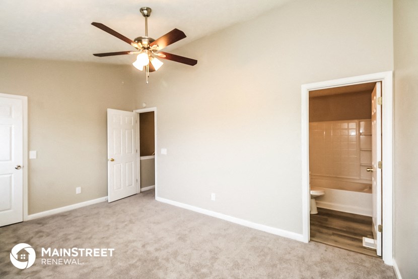 an empty living room with a ceiling fan and a bathroom