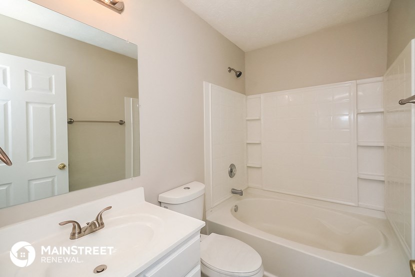 a white bathroom with a tub and a sink and a mirror