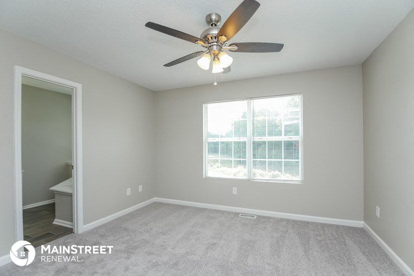 the master bedroom has a ceiling fan and a large window