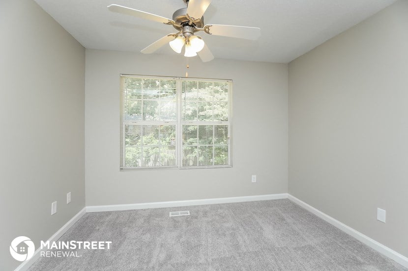 the master bedroom has a large window and carpeted flooring