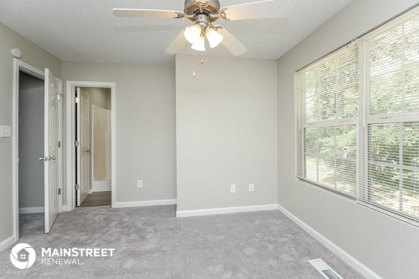 the master bedroom has a ceiling fan and a large window