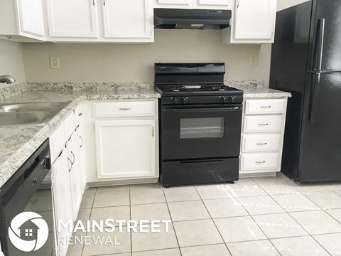 a kitchen with white cabinets and a black stove and refrigerator