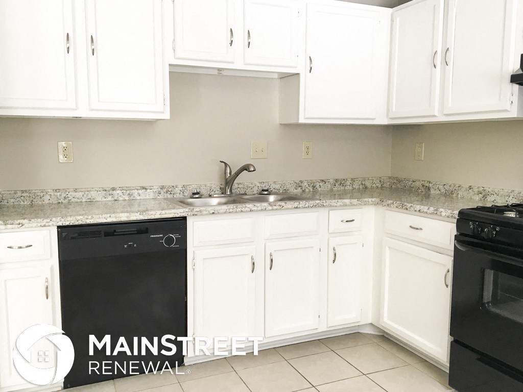 a white kitchen with white cabinets and black appliances