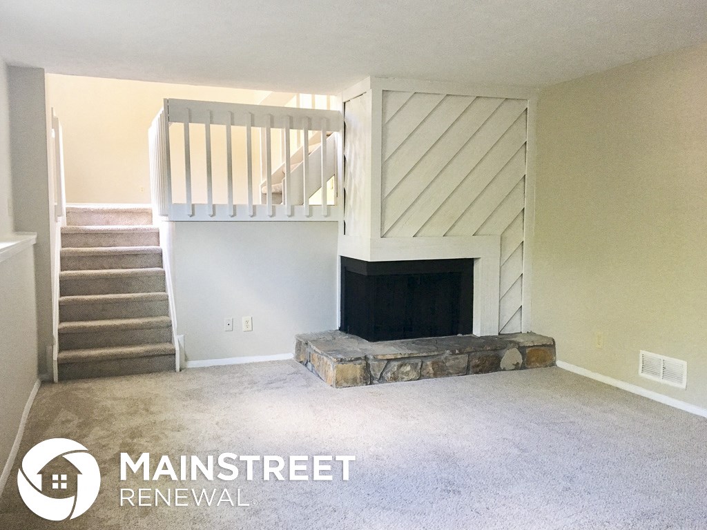 an empty living room with a fireplace and stairs