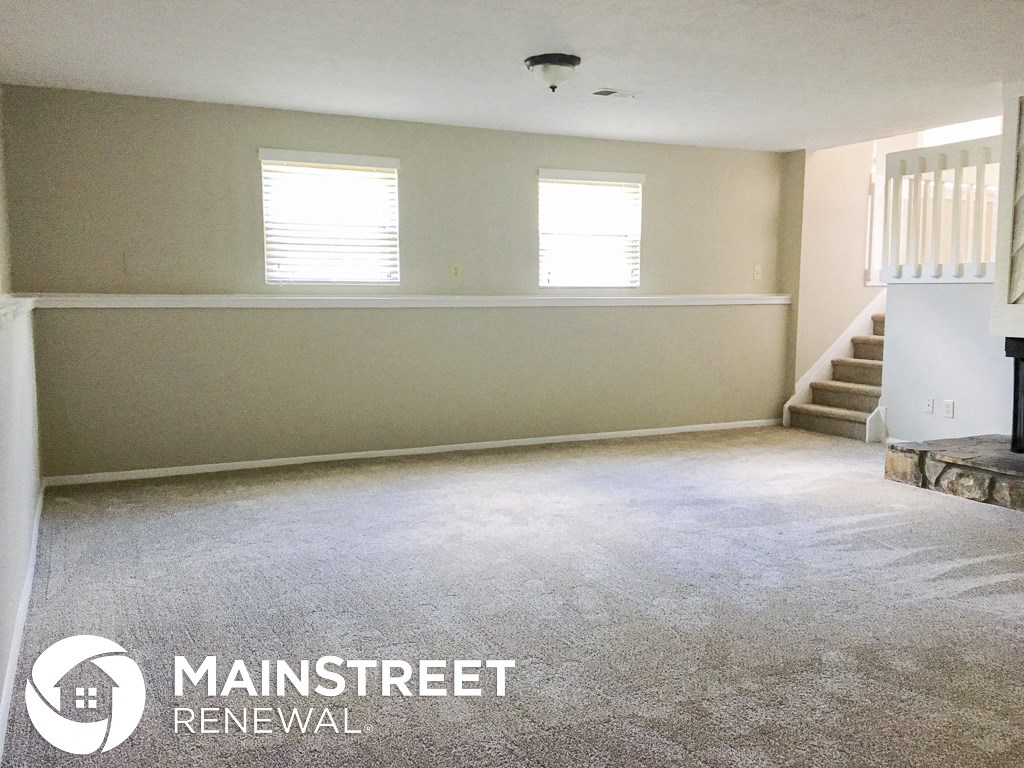 an empty living room with a carpeted floor and two windows