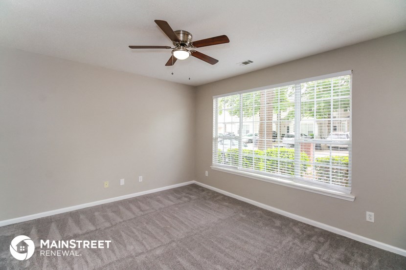 the living room has a large window and a ceiling fan